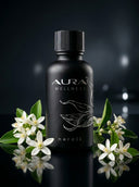 Black bottle of Aura Wellness neroli oil with flowers on a dark background